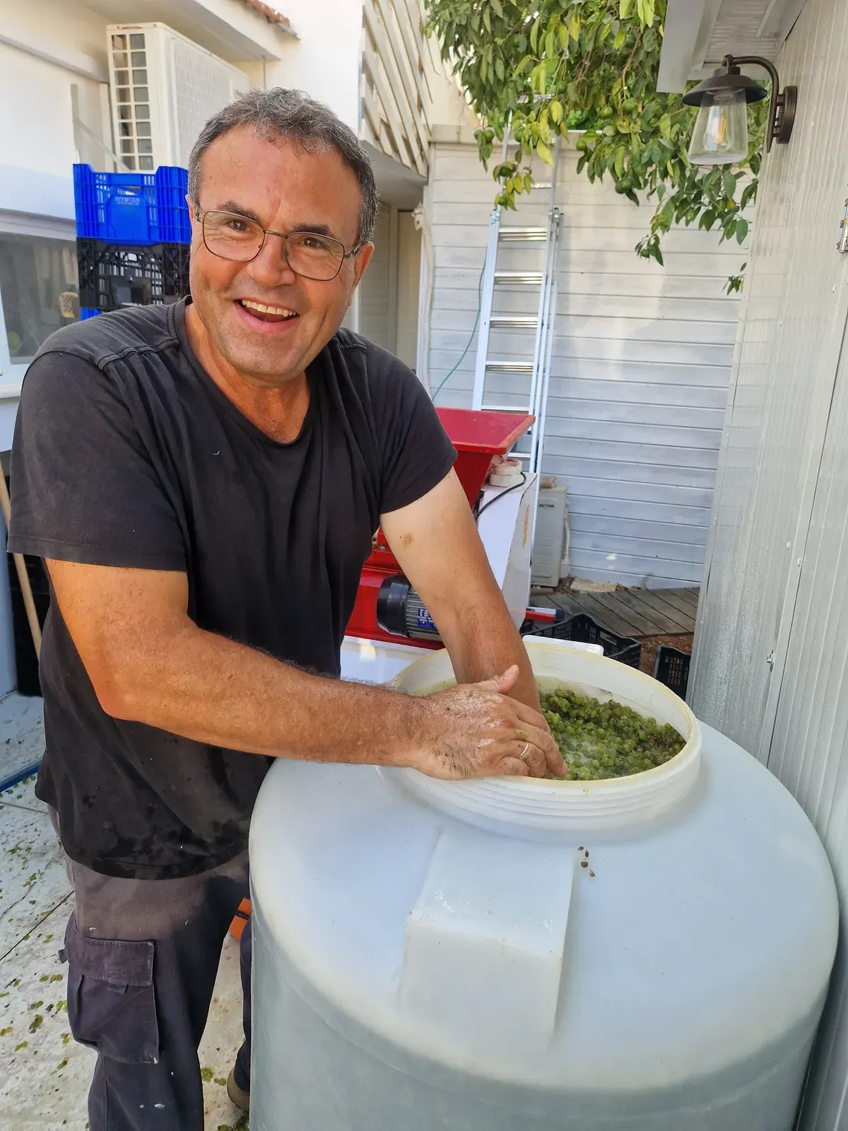 יואב מחייך ומערבב את התירוש במכל